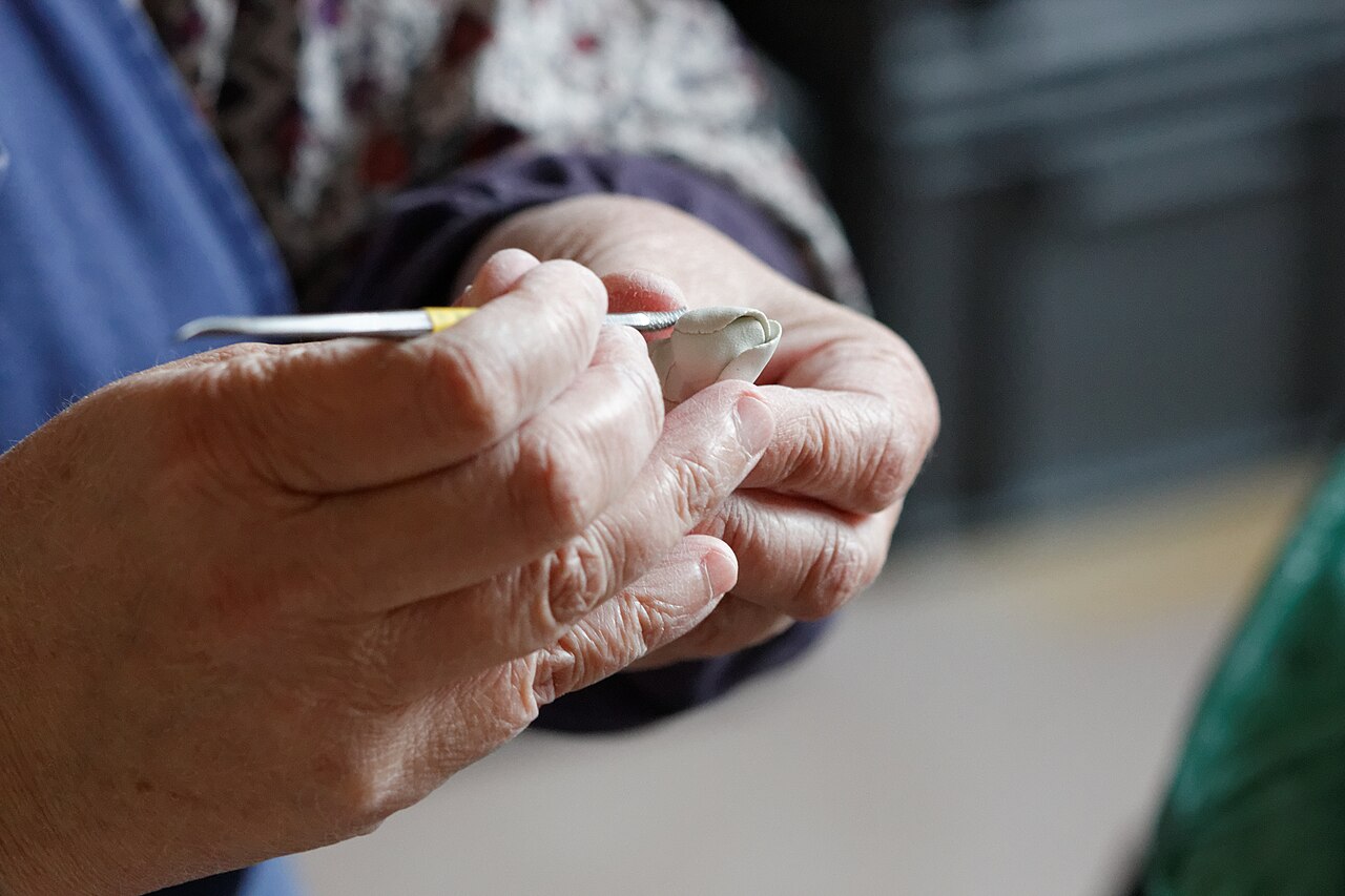 Hands shaping ceramic details in a Sèvres workshop.